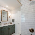 White beadboard wainscoting installed on the walls of a modern bathroom with green vanity.