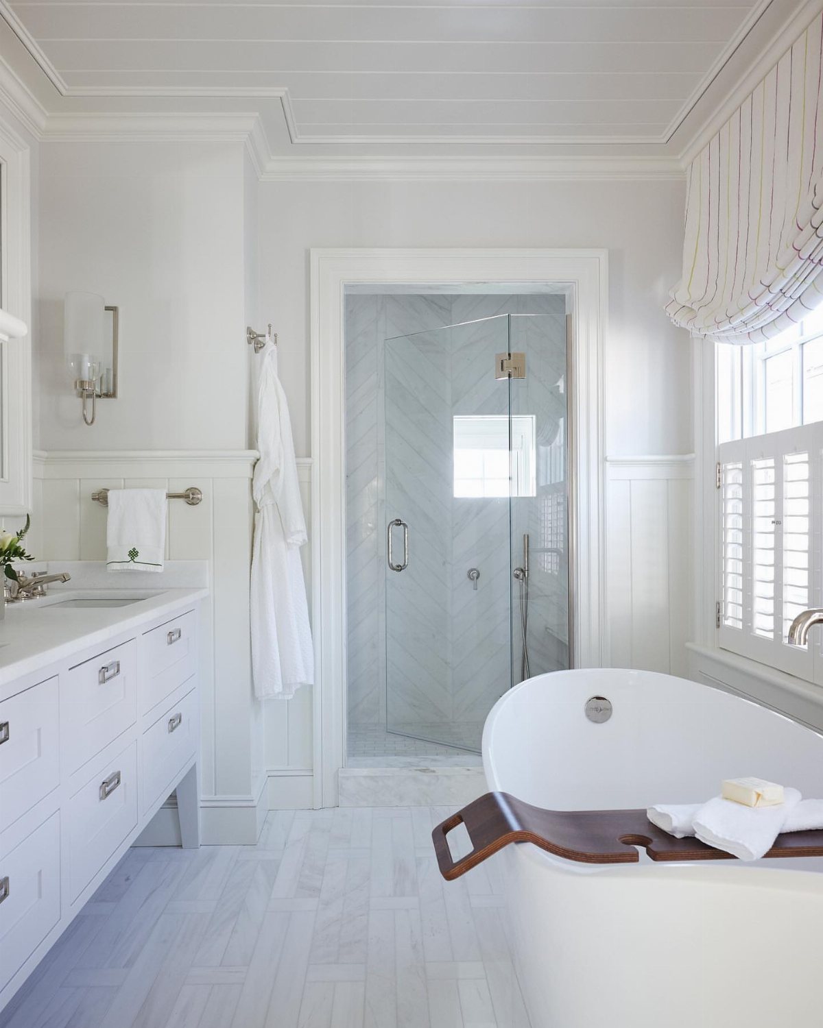 A bright white bathroom with a soaking tub, vanity, glass shower, and beadboard ceiling.