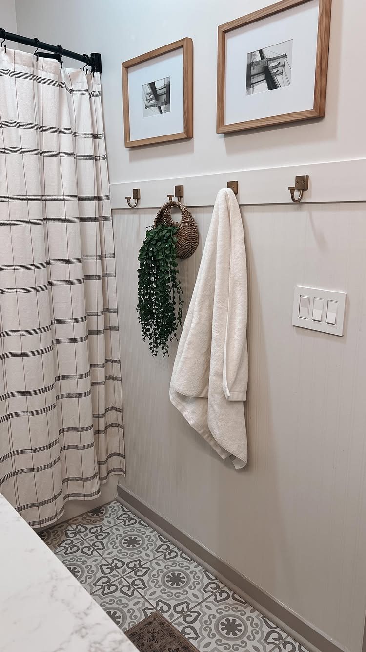 White towel and green plant hanging on a grey beadboard wall in a bathroom.