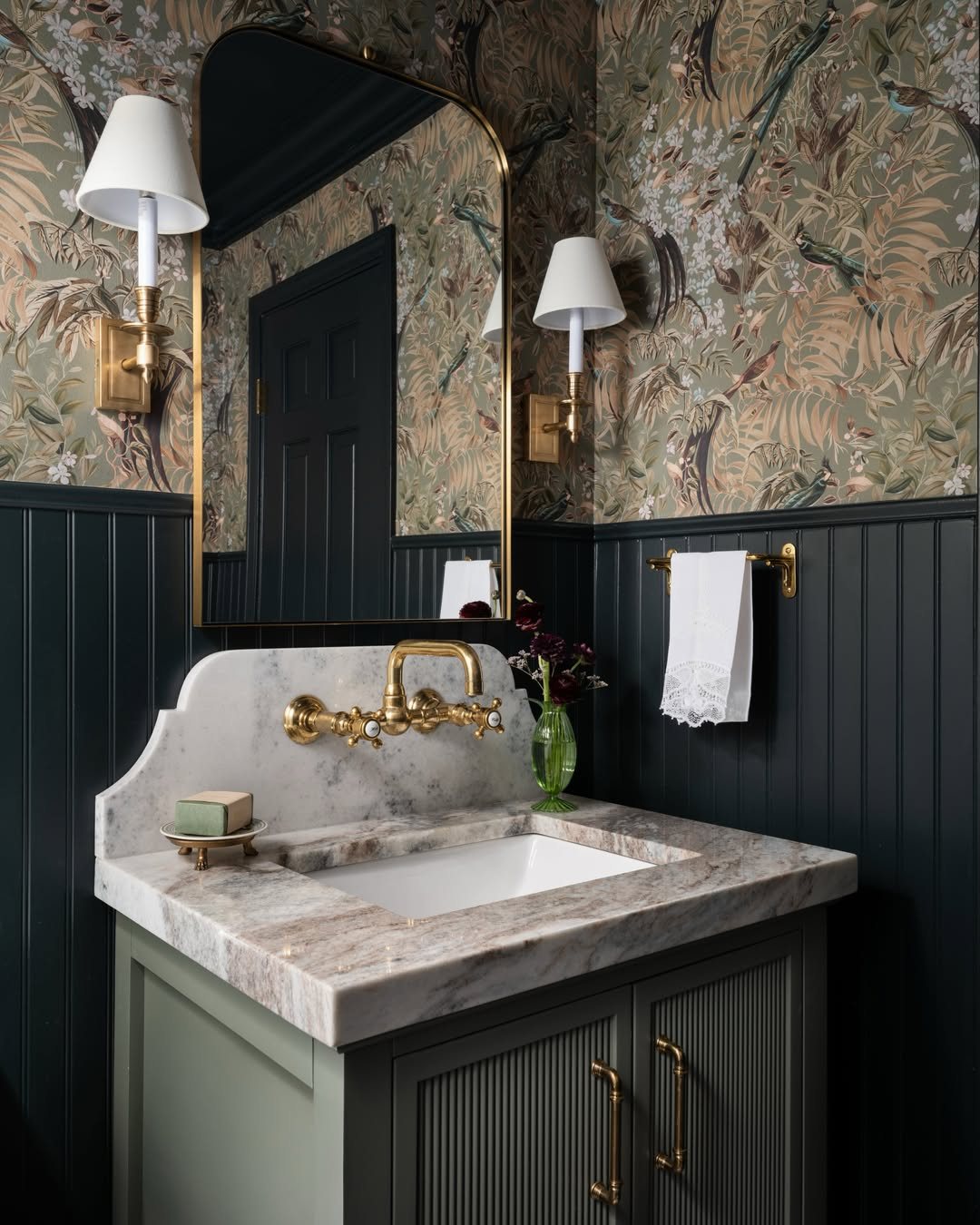 Dark charcoal beadboard wainscoting paired with botanical wallpaper in a luxury bathroom setting.