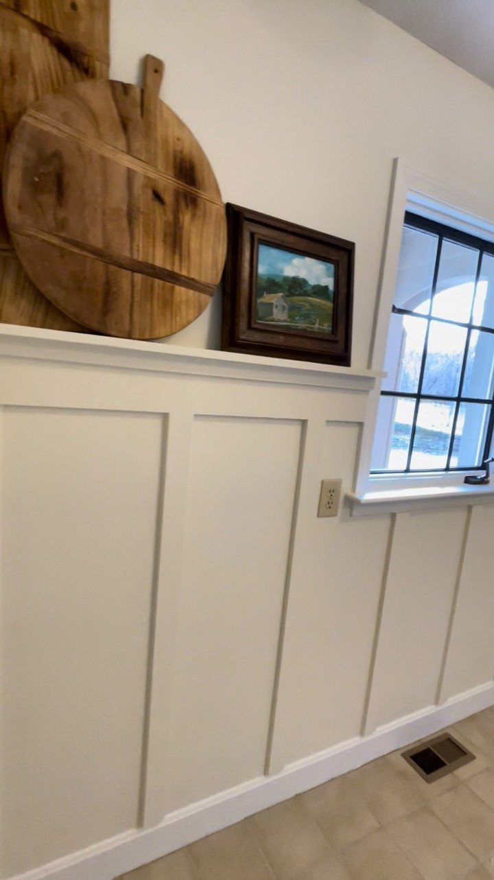 White board and batten wall trim with wooden decor and a window.