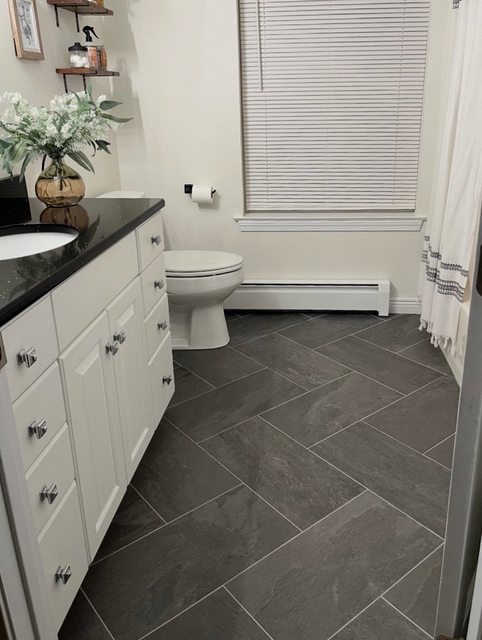 Dark grey large-format tiles in a herringbone pattern on a bathroom floor.