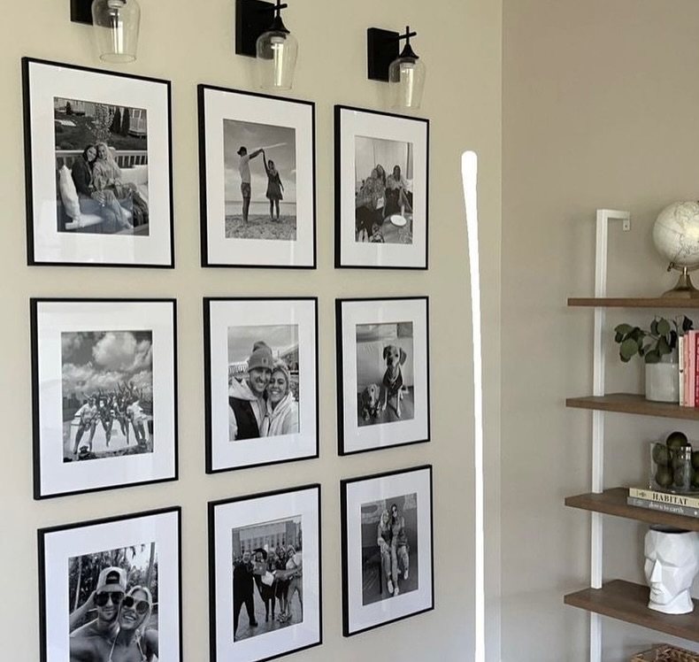 Nine black-framed black and white photographs arranged in a grid on a beige wall.