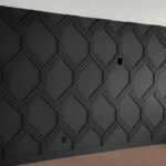 Dark charcoal wall with a raised three-dimensional geometric pattern of interlocking lines.
