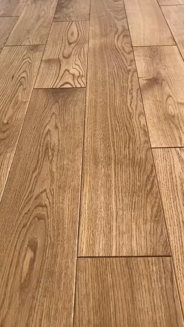 Wide plank light brown wood flooring with prominent natural grain patterns and smooth finish.