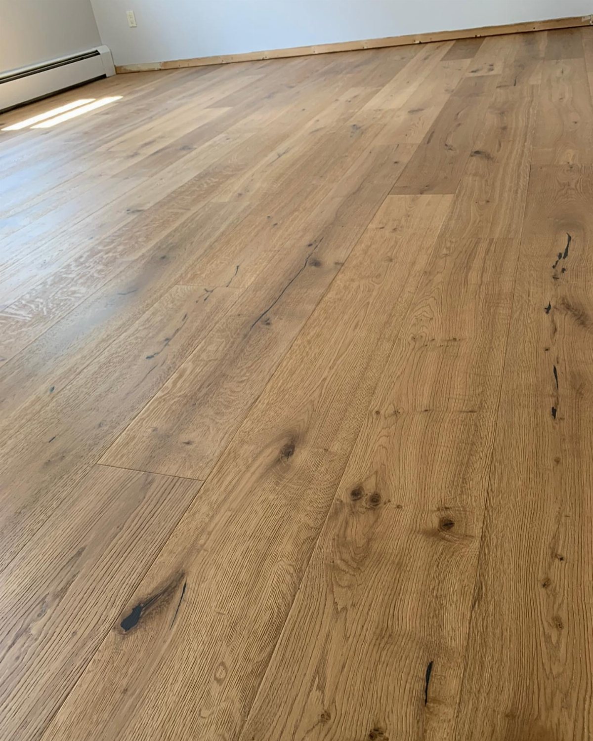 Wide plank French oak flooring with visible wood grain and knots in a room.
