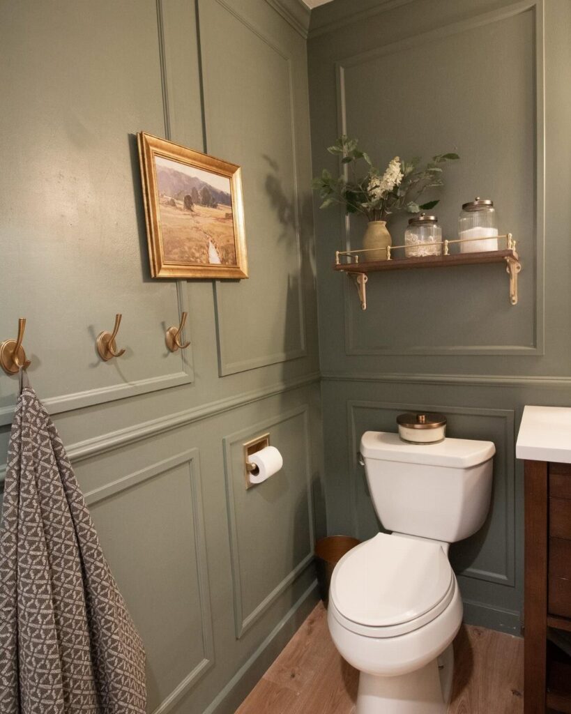 Sage green wainscoting paneling installed on the lower half of a bathroom wall near a white toilet.