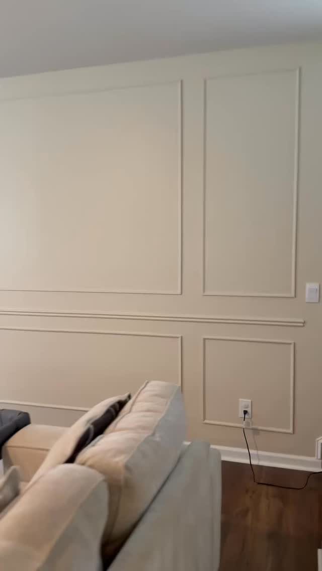 Beige wall decorated with large and small rectangular picture frame moulding panels.