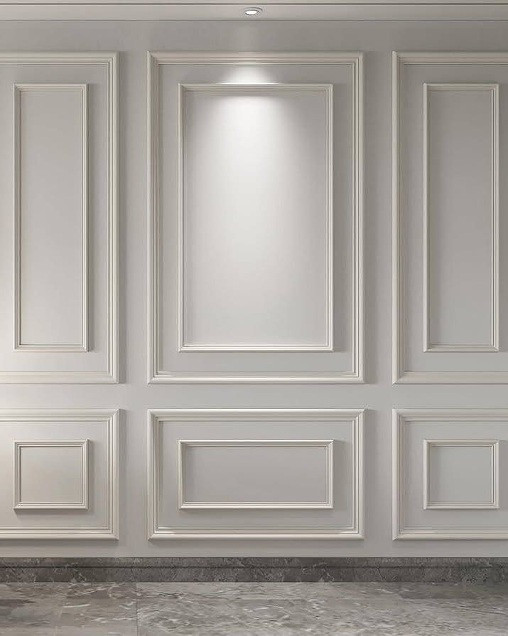 Decorative grey wall panels featuring various rectangular picture moulding designs under soft lighting.