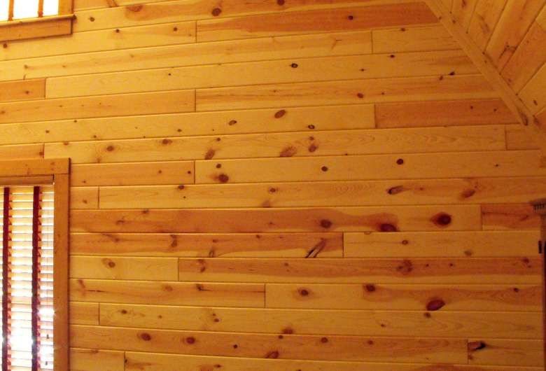 Horizontal pine wood planks with natural knots forming a warm golden shiplap wall.
