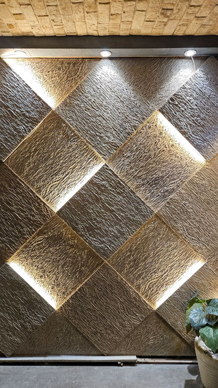 Textured gold diamond-shaped tiles on a wall with warm light glowing from the seams.