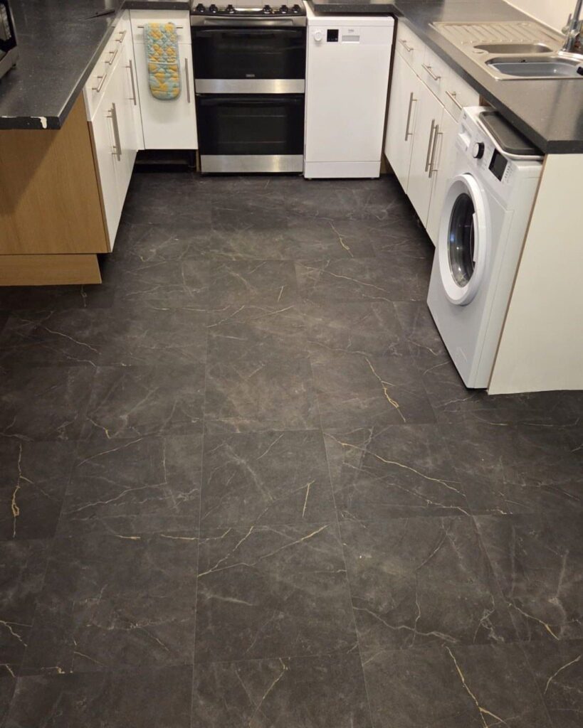 Dark grey marble-effect vinyl flooring tiles installed in a modern kitchen setting.