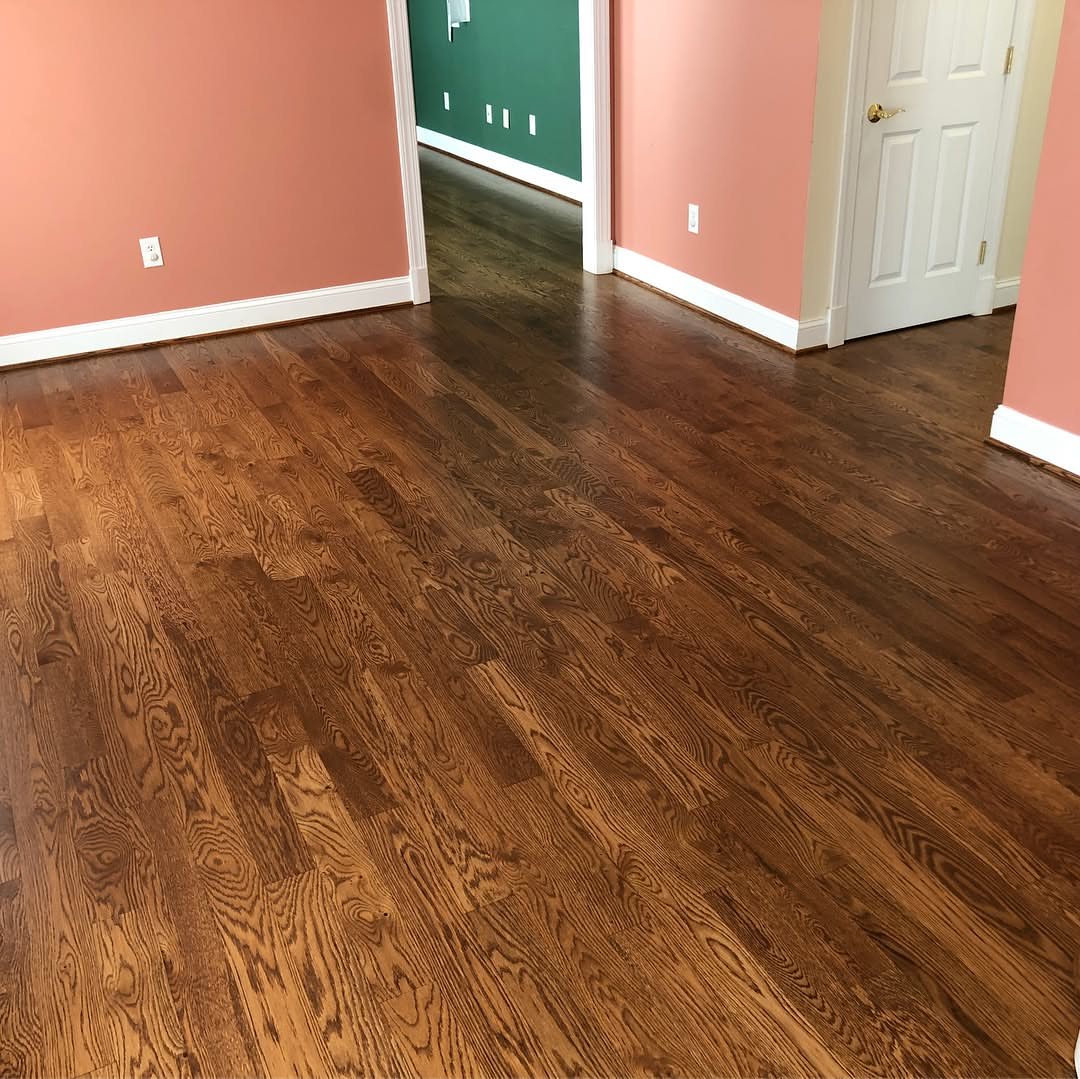 Dark brown stained hardwood flooring installed in a room with peach walls and white trim.