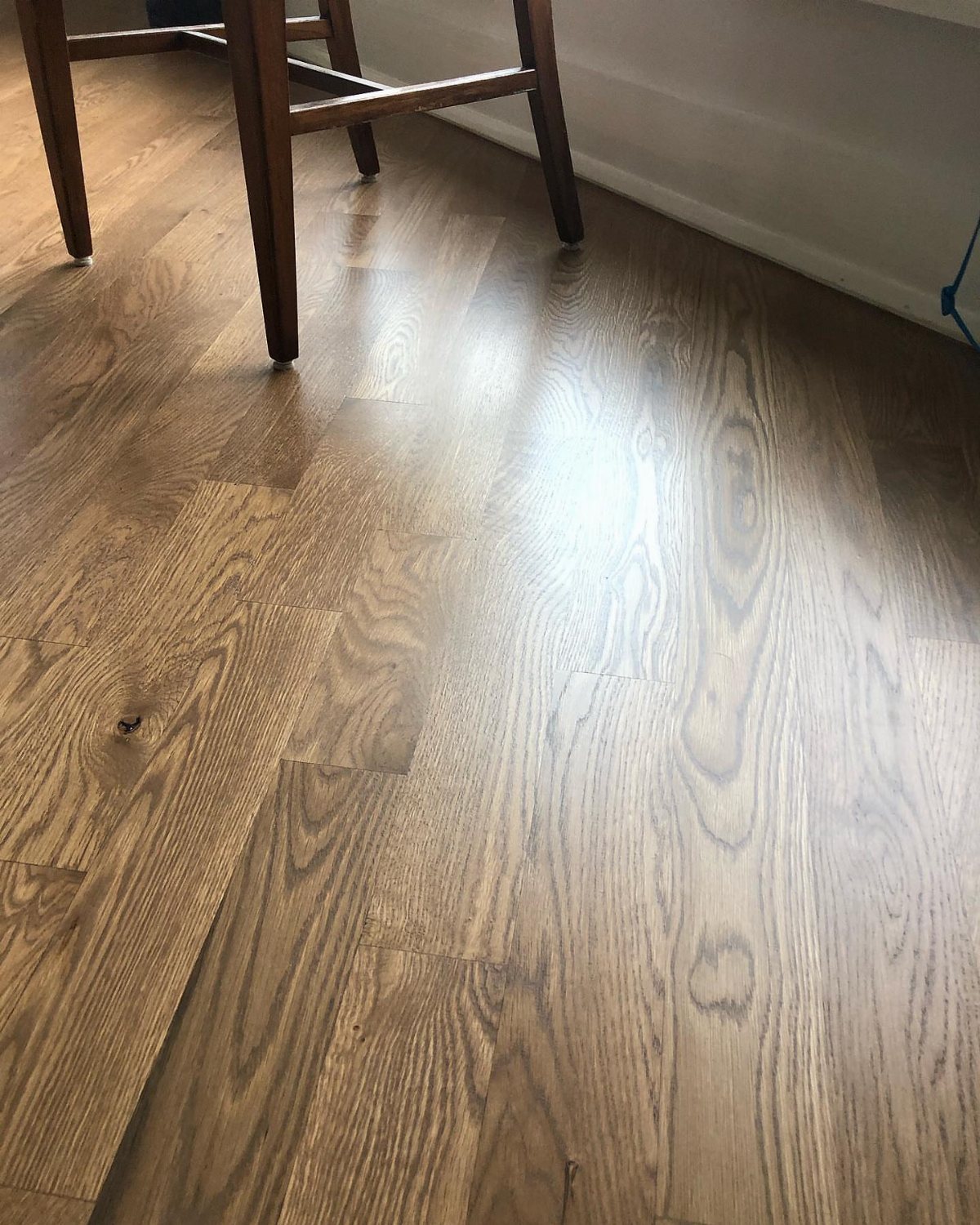 Finished white oak hardwood flooring with a medium brown stain and visible wood grain patterns.