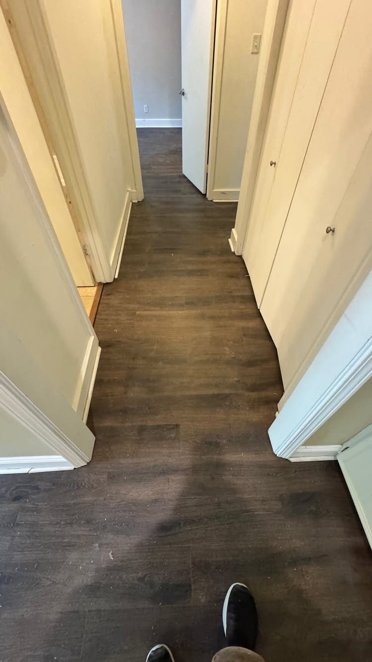 11 Whole House Flooring Ideas That Work from Entry to Bedroom 7 Dark wood-look flooring running continuously through a hallway and into an open doorway.