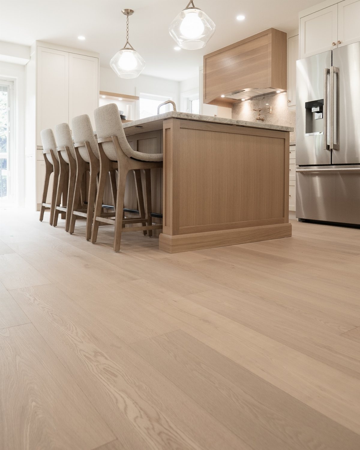 11 Whole House Flooring Ideas That Work from Entry to Bedroom 5 Light wood plank flooring in a bright, modern kitchen with a wooden island and white cabinets.