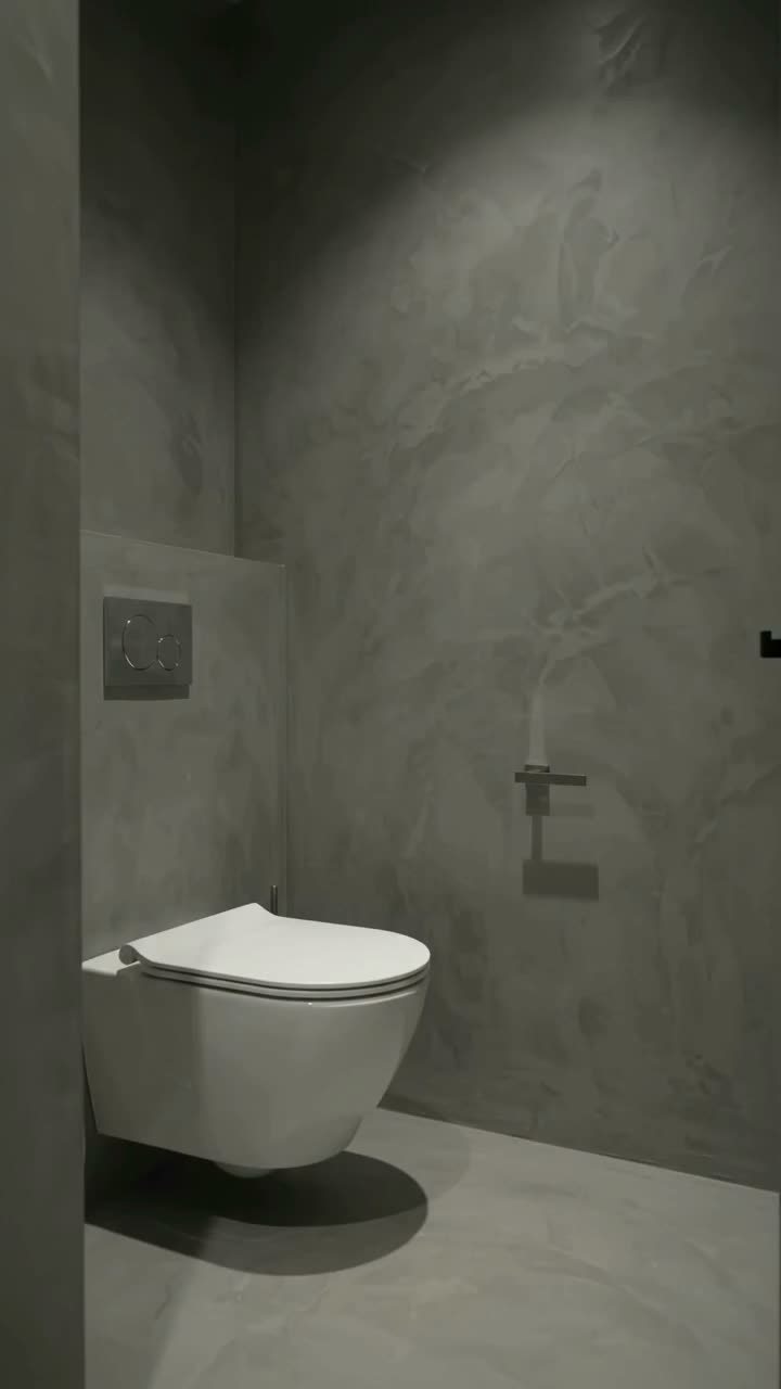11 Whole House Flooring Ideas That Work from Entry to Bedroom 9 A white wall-mounted toilet in a minimalist bathroom with grey microcement walls and floor.