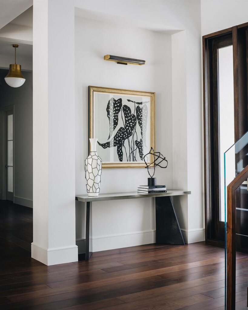 Dark walnut wood flooring in a modern interior hallway with a white console table and artwork.