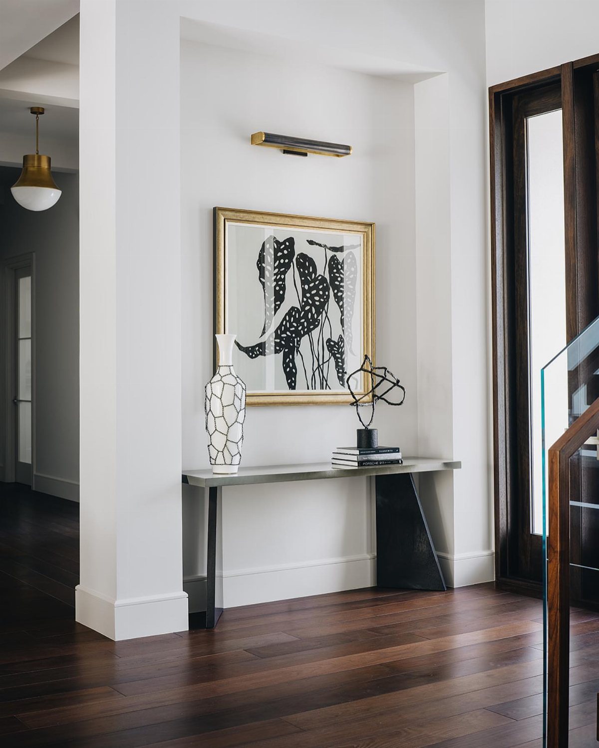 Dark walnut wood flooring in a modern interior hallway with a white console table and artwork.