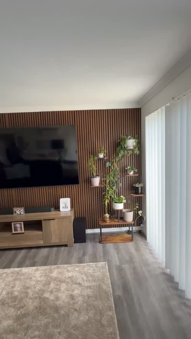 A large television mounted on a dark wood slat accent wall in a living room.