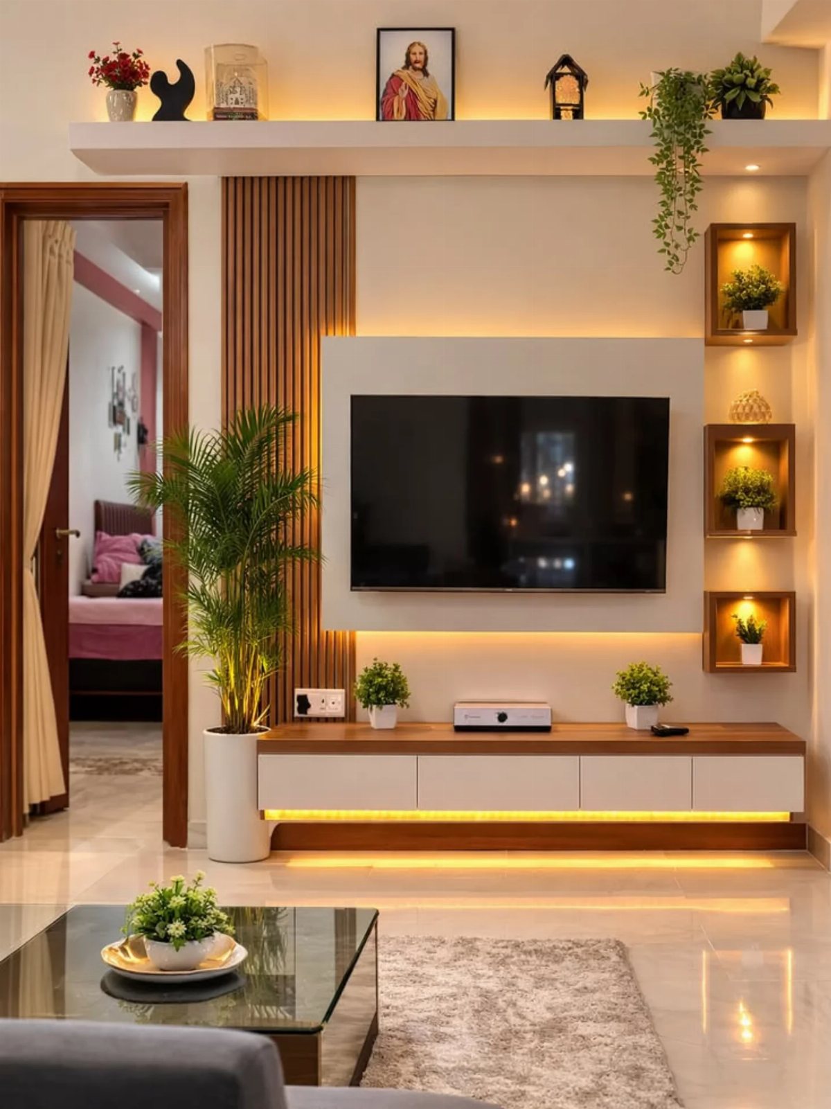 A television mounted on a white wall with vertical wood paneling and warm accent lighting.
